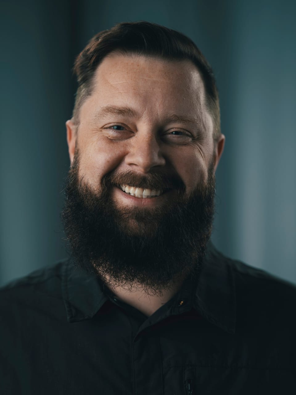Mateusz Piekut, founder of Saiokatta, smiling in a dark shirt against a teal background